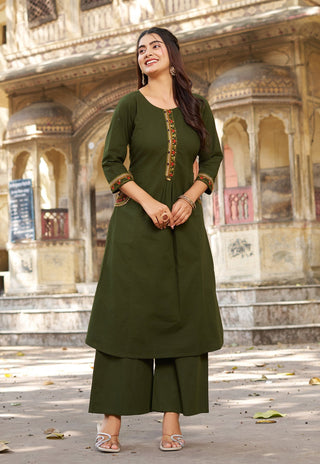 Woman in a green traditional outfit standing in front of an architectural background