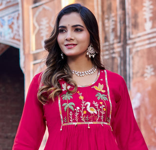 Woman wearing a red embroidered dress with a decorative background