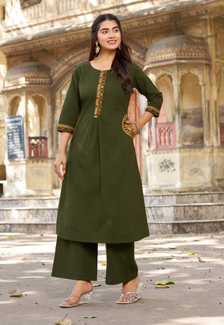Woman in a green traditional outfit standing in front of an architectural background